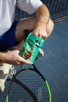 a man holding a bag of chips on top of a tennis racket