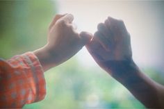 two people holding hands in front of a window