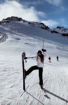 a woman standing on skis in the snow with her arms up and legs spread out