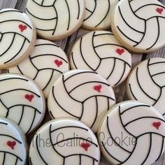 decorated cookies with white icing and red hearts are arranged in the shape of a volleyball ball