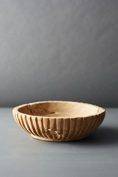 a wooden bowl sitting on top of a gray table next to a white wall and floor