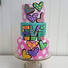 a three tiered cake decorated with hearts and the word love on it's side