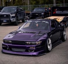 a purple car parked in a parking lot next to other cars and trucks behind it