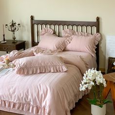 a bed with pink sheets and ruffled pillows