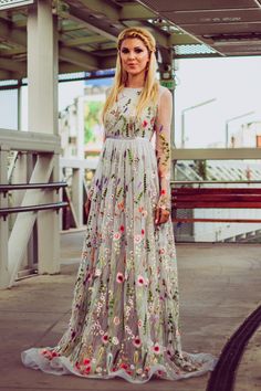 a woman in a long dress standing on a sidewalk