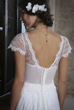 the back of a woman's wedding dress with flowers in her hair is shown