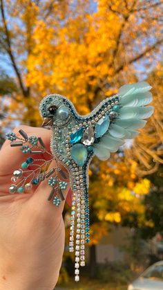 a hand holding a brooch with a bird on it