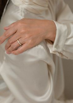 a woman's hand wearing a wedding ring on top of her white dress shirt