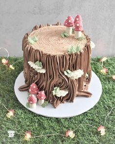 a cake that is sitting on top of a plate in the grass with mushrooms around it