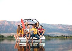 a group of people sitting on top of a boat in the middle of a lake