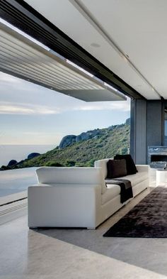 a modern living room with white furniture and large windows overlooking the water's edge