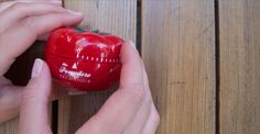 a person is holding a red heart shaped container