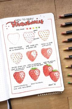 an open notebook with strawberries drawn on it and colored pencils next to it