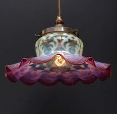 a colorful glass light hanging from a ceiling fixture with a small bulb in the center