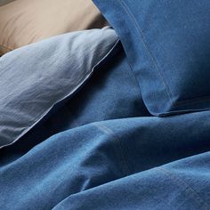 a bed with blue denim sheets and pillows