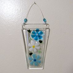 a glass ornament with flowers hanging from it's side on a wall