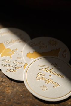 four white and gold wedding coasters sitting on top of a wooden table