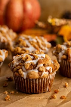 muffins with white icing and pumpkins in the background on a table