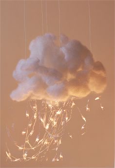 a cloud that is floating in the air with lights on it's sides and some strings hanging from them