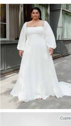 a woman in a white wedding dress standing on the sidewalk with her hands on her hips