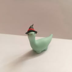 a small green bird with a hat on it's head sitting on a table