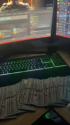 several stacks of money sitting on top of a computer keyboard next to a desktop monitor