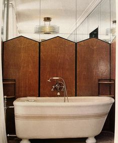 an old fashioned bathtub in a bathroom with wooden paneling and mirrors on the wall