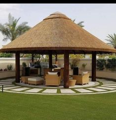 a gazebo in the middle of a grassy area with chairs and tables around it