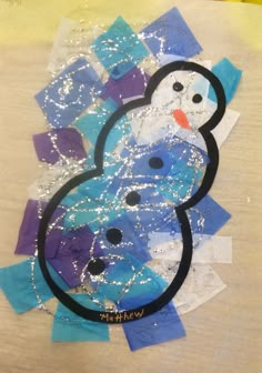 a snowman made out of pieces of paper and some glitter on top of it