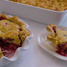 two plates with pies on them next to a dish full of strawberry cobbles