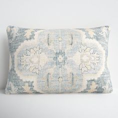 a blue and white pillow with an intricate design on the front, sitting against a wall