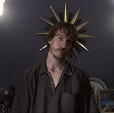 a man standing in front of a wall with a sun decoration on it's head