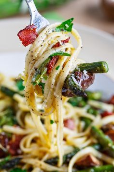 a fork full of spaghetti with asparagus and bacon