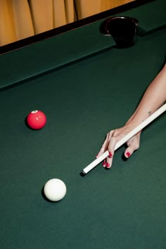 a woman is playing pool with her cues and ball on the green clothed table