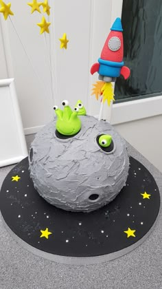 a birthday cake made to look like a space ship on top of a rock with stars around it