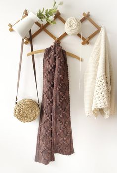 a scarf hanging on a coat rack next to a basket and cup holder with yarn