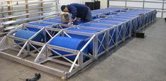 a man working on some blue tanks in a warehouse