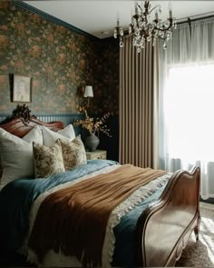 a bed sitting in a bedroom next to a window with curtains on both sides and a chandelier hanging from the ceiling