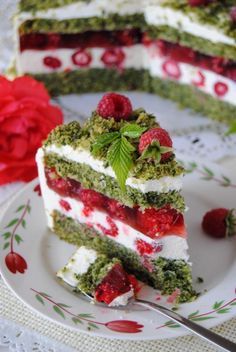 a piece of cake on a plate with raspberry toppings and green leaves