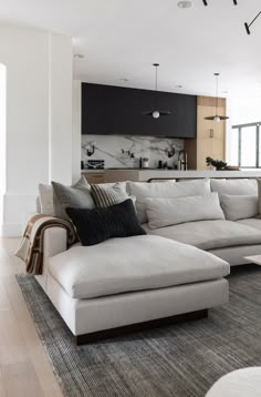 a living room filled with furniture and a large white couch in front of a kitchen