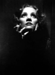 a black and white photo of a woman with her hand on her chin looking up