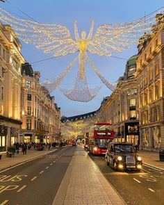 a street with cars, buses and christmas lights strung across the road in front of buildings