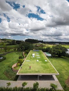 an aerial view of a green field with people standing on it