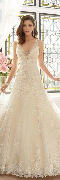 a woman in a wedding dress standing next to a window with flowers on it and looking at the camera