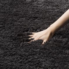 a woman's feet on a shaggy rug with her hand reaching for the carpet