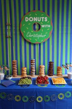 a blue table topped with lots of food and desserts next to a striped wall