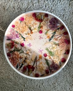 a white bowl filled with flowers on top of a carpet