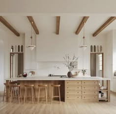 a large kitchen with wooden floors and white walls, along with two bar stools