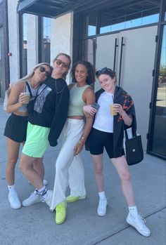 four girls posing for the camera in front of a building