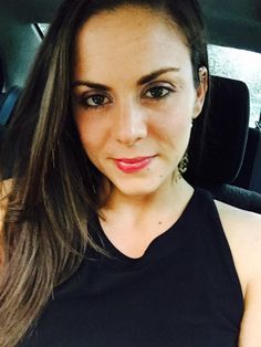 a woman sitting in the back seat of a car wearing a black top and earrings